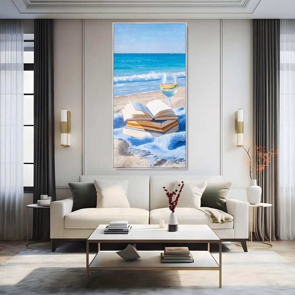 Tablou canvas cu pictura cu carti si pahar de vin pe plaja, in rama de aluminiu argintiu, pe perete intr-un living